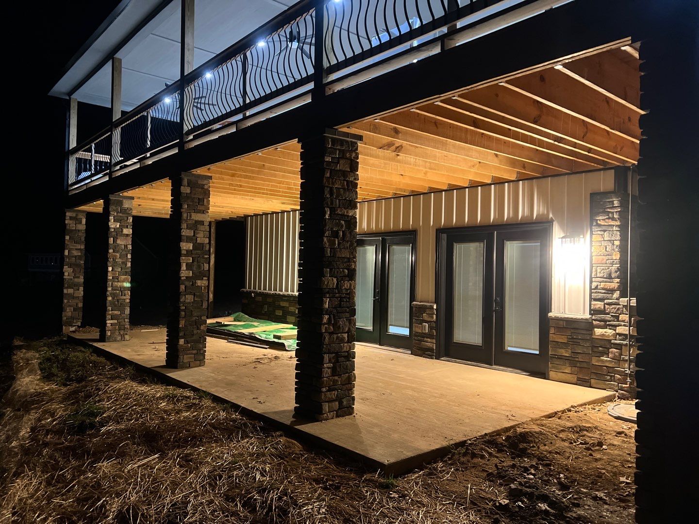 Covered patio with stone columns and wood ceiling at night