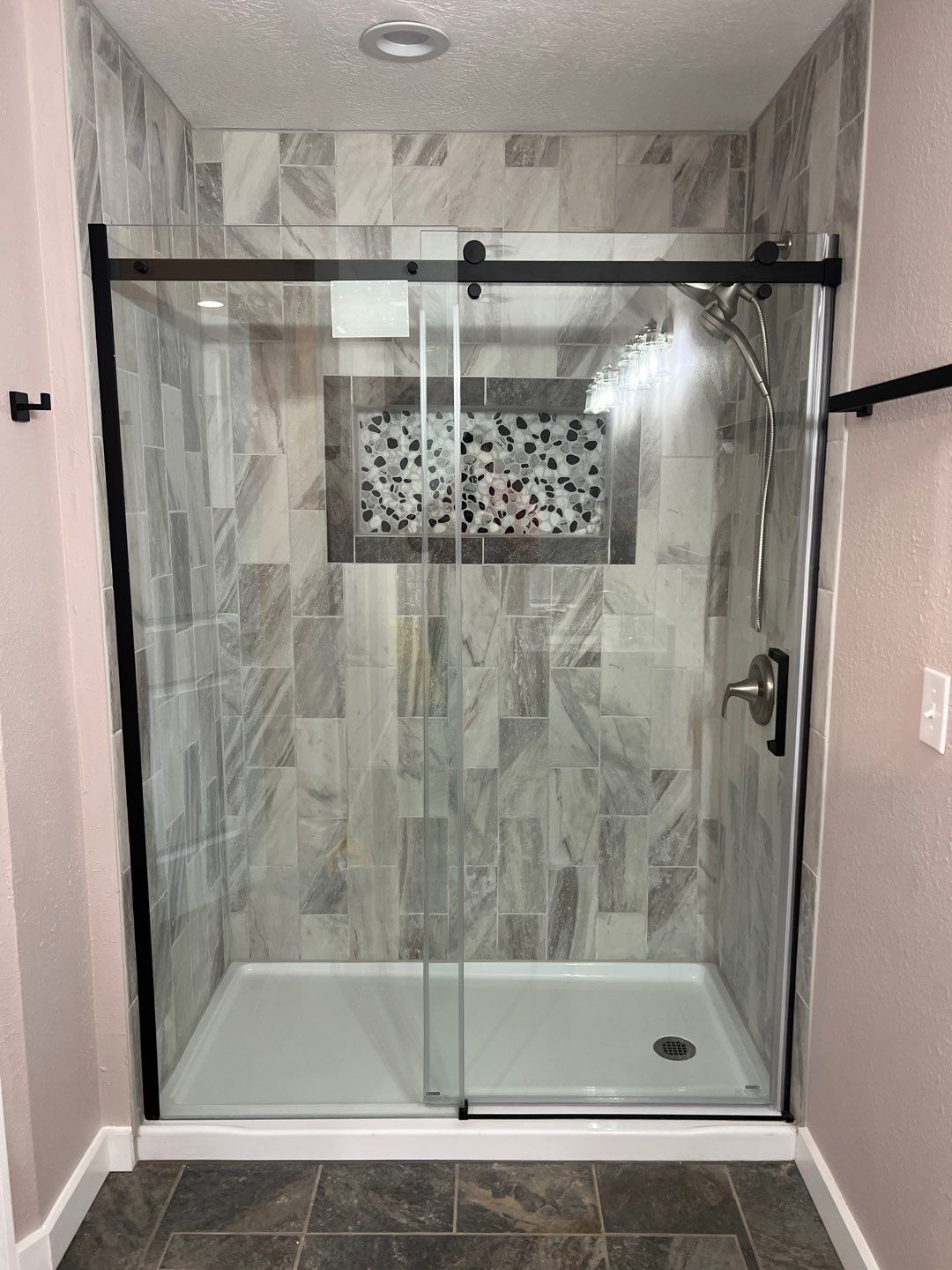 Custom tile shower with marble finish and glass door