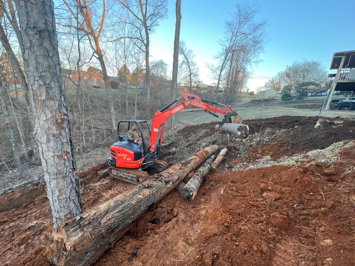 Mini excavator clearing and moving logs