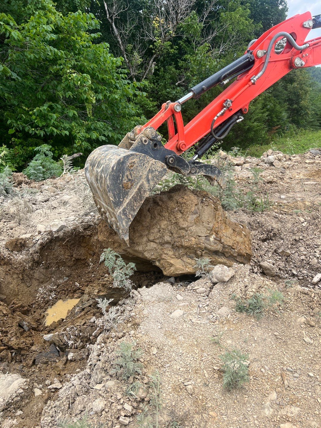 Excavator bucket removing large boulder