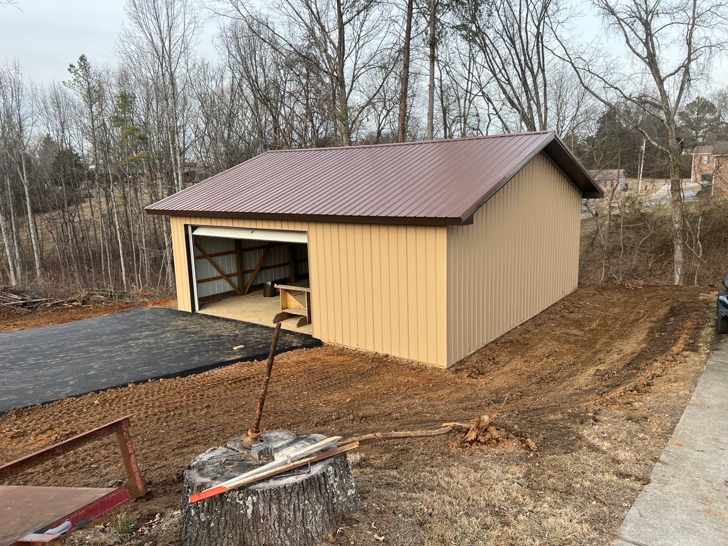 Completed pole barn with tan siding and metal roof